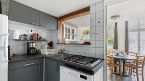 A modern kitchen with grey cabinets, a gas stove, and a dining area with a table and chairs.
