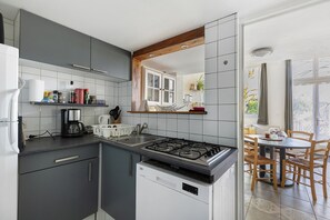 A modern kitchen with grey cabinets, a gas stove, and a dining area with a table and chairs.