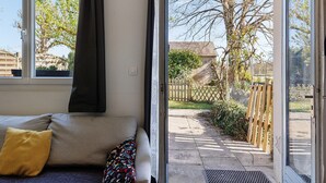 A room with a sofa, a window, and a view of a garden.