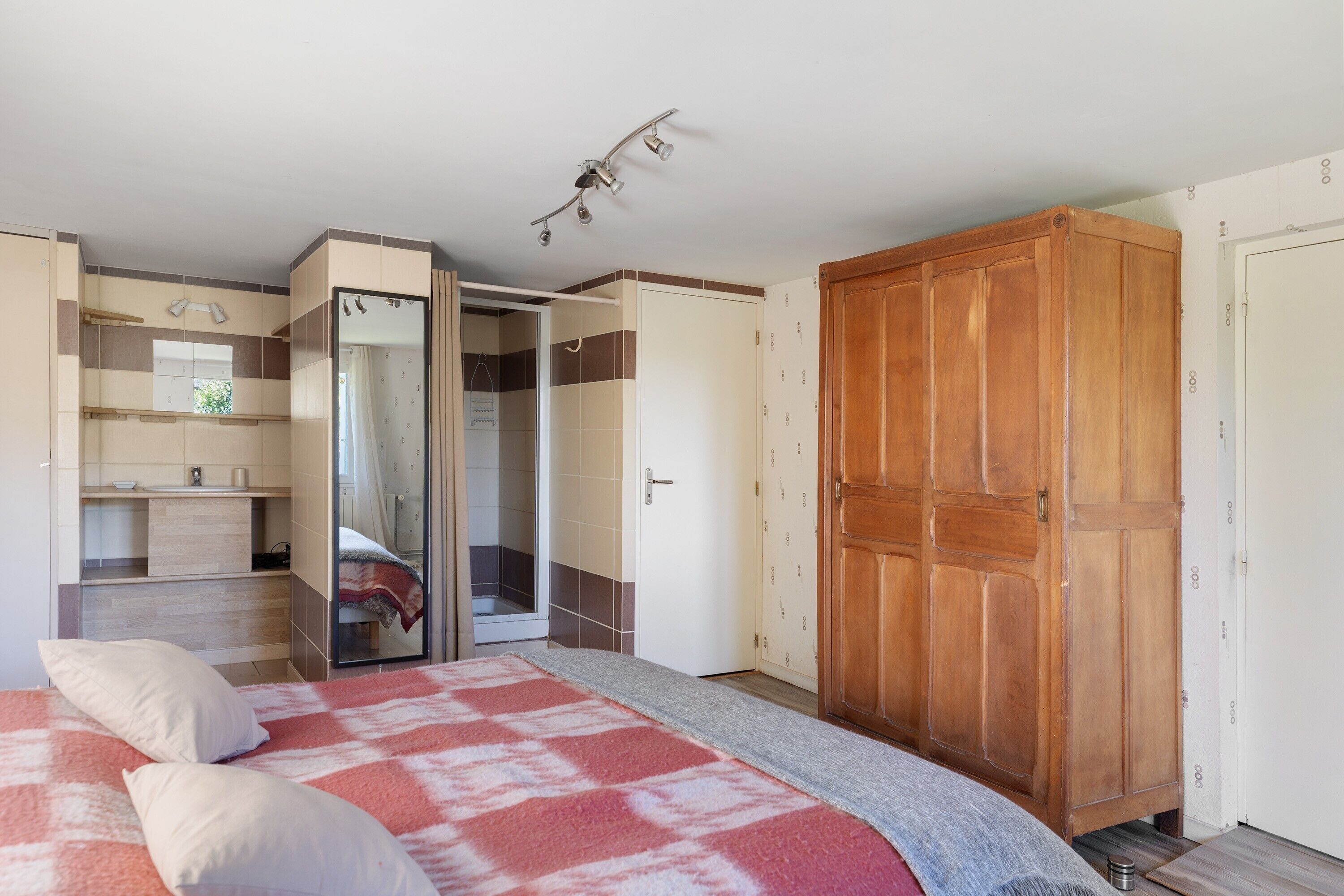 Un dormitorio con cama, armario, baño y ropero.