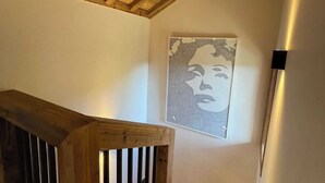 Una escalera de madera con barandilla de madera y un cuadro colgado en la pared.
