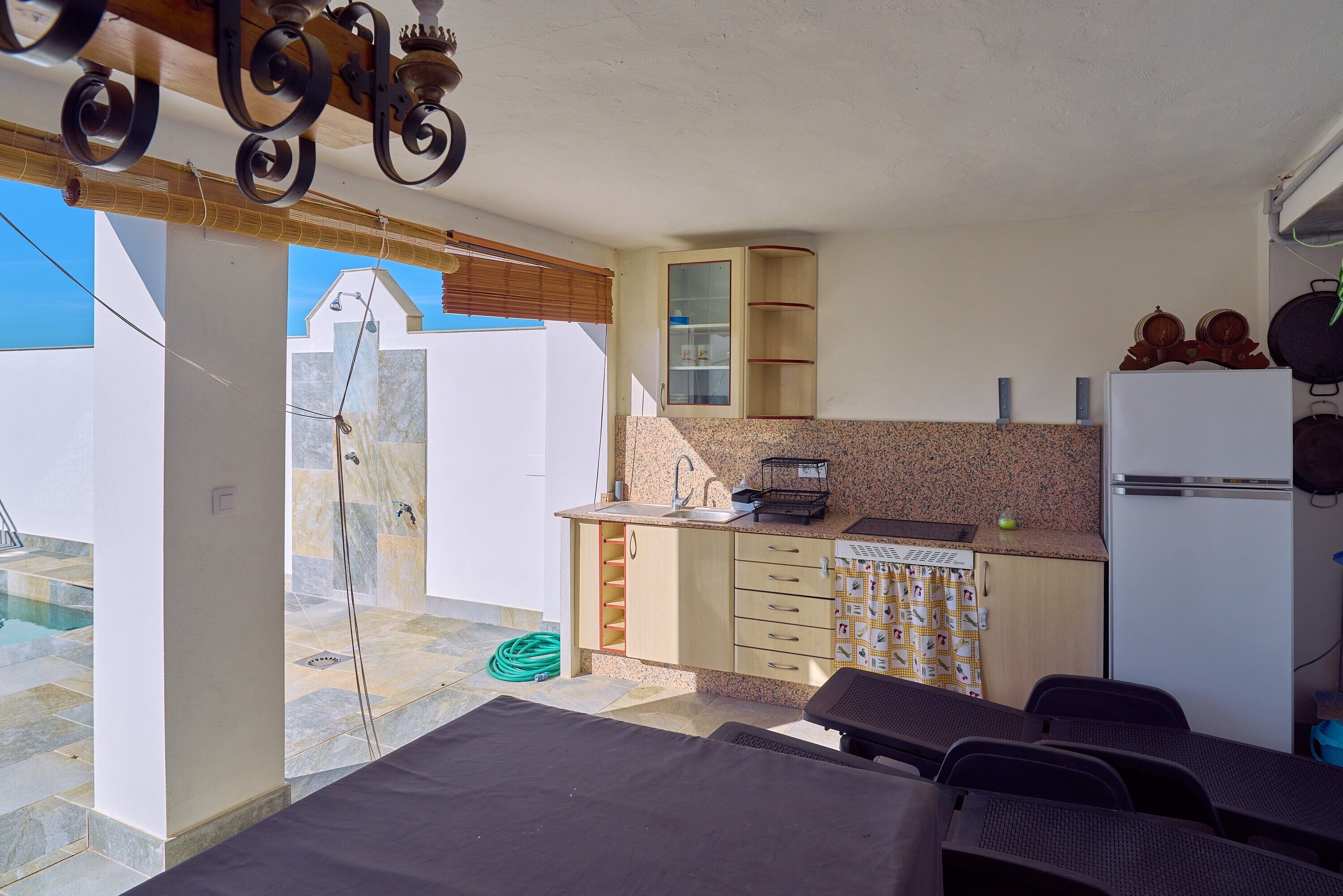 Una cocina compacta con lavamanos, encimera y refrigerador. Hay un pequeño comedor con sillas y una mesa.
