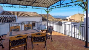 A covered outdoor patio with a table and chairs, a view of the cityscape, and a metal railing. - Country House 'Romo 2' with Mountain View, Wi-Fi and Air Conditioning (Rute)