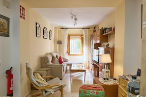 A living room with a sofa, armchair, coffee table, and a television. There is a fire extinguisher on the wall and a window with curtains. - Country House 'Romo 2' with Mountain View, Wi-Fi and Air Conditioning (Rute)