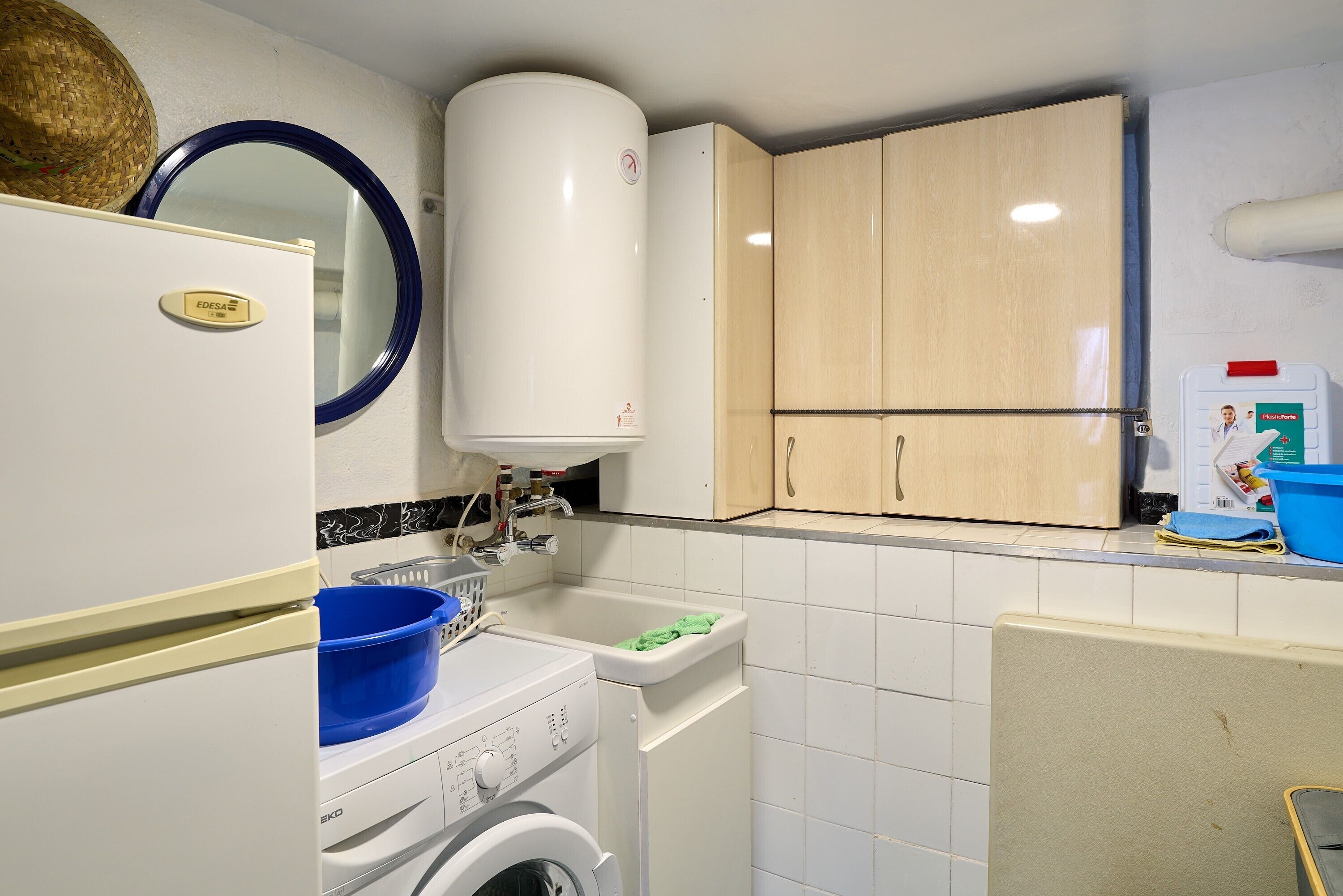 A compact kitchen with a washing machine, a sink, and wooden cabinets.