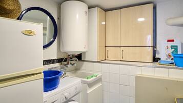 A compact kitchen with a washing machine, a sink, and wooden cabinets.