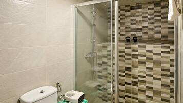 Une salle de bain avec une douche à parois de verre, des toilettes et un lavabo.