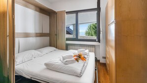 A hotel room with a bed, a window, and wooden walls. - Grange Studio (Sauze di Cesana)