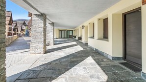 A covered corridor with stone flooring, a stone pillar, and a door on the right. - Grange Studio (Sauze di Cesana)