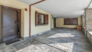 A stone-floored hallway with a wooden door and window, a stone wall, and a stone staircase. - Grange Studio (Sauze di Cesana)