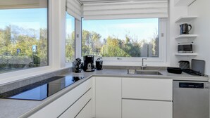 Eine moderne Küche mit großem Fenster, eingebauten Geräten und einem Geschirrspüler.