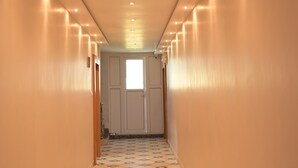 A long, narrow hallway with a patterned floor and recessed lighting. - Nirmalya Guest House (Brahmapur)