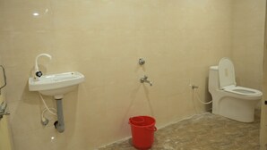 A bathroom with a sink, toilet, and shower. - Nirmalya Guest House (Brahmapur)
