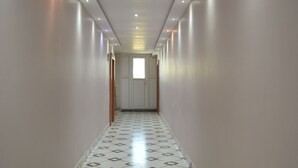 A long, narrow hallway with patterned flooring and recessed lighting. - Nirmalya Guest House (Brahmapur)