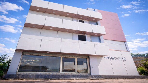 A multi-story building with a modern design, featuring a prominent sign for 'Nirmalya Guest House' on the lower right side. - Nirmalya Guest House (Brahmapur)