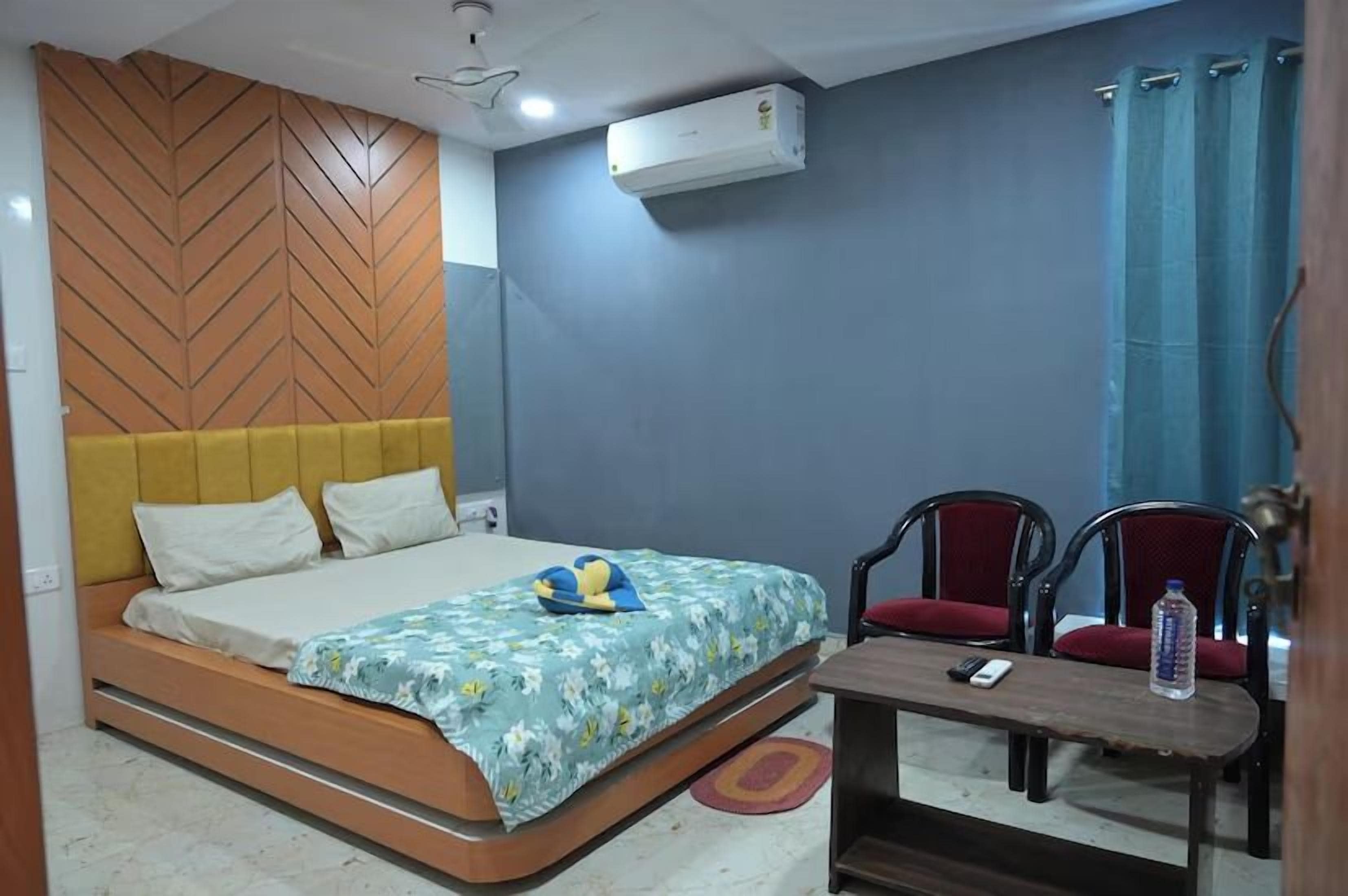 Un dormitorio con cama, dos sillas, una mesa y un ventilador de techo.