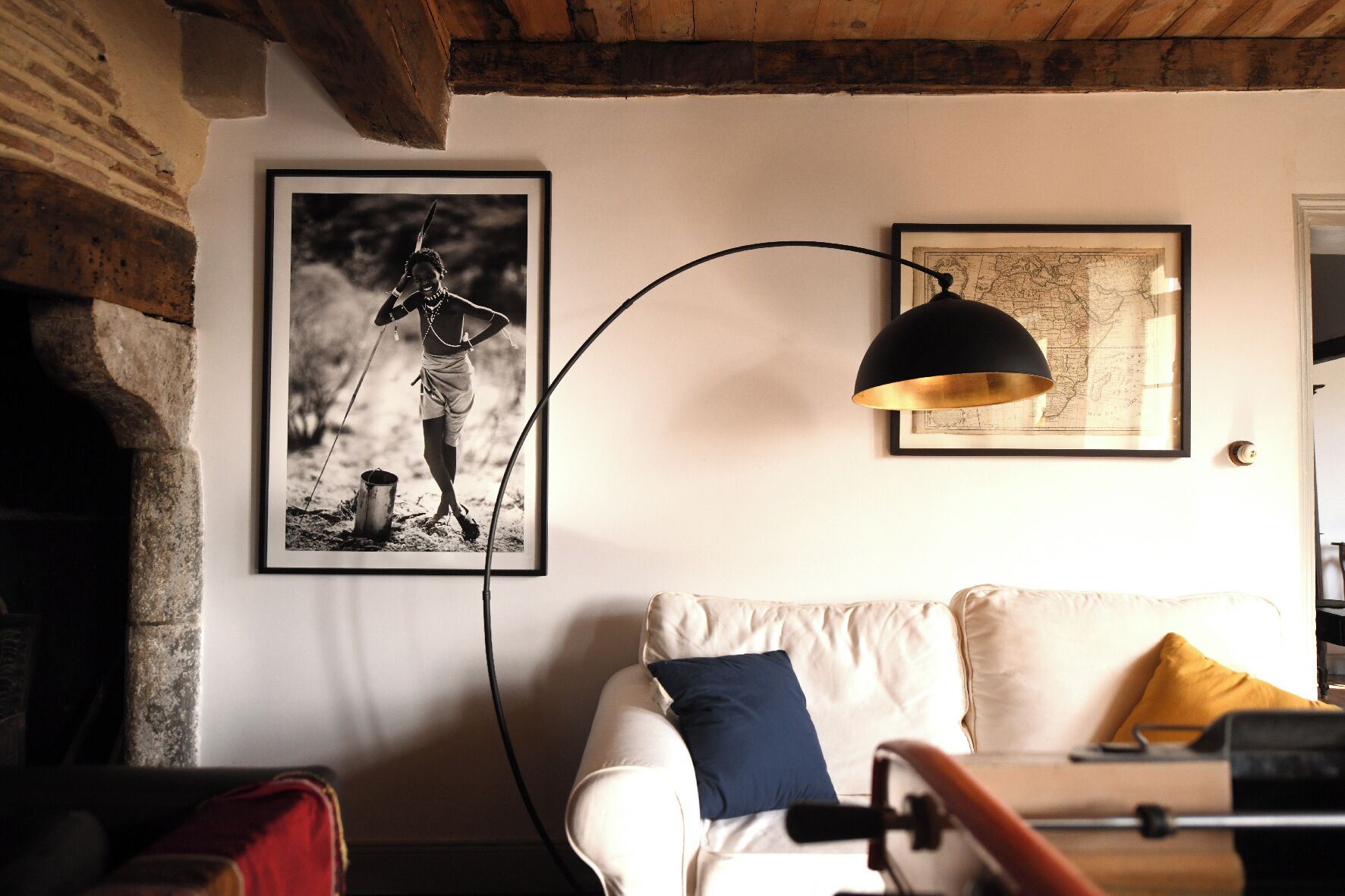 Une pièce avec un canapé blanc, une carte et une photographie encadrée accrochée au mur.
