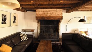 Ein gemütliches Wohnzimmer mit Kamin, Holzbalkendecke und zwei Sofas.