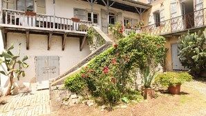 Ein Gebäude mit einer Treppe, die zu einem Balkon führt, umgeben von Kakteen und blühenden Pflanzen.