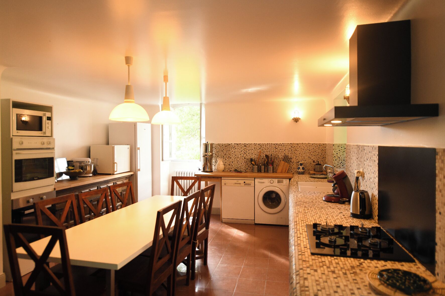 A compact kitchen with a dining area, a washing machine, and a coffee machine.