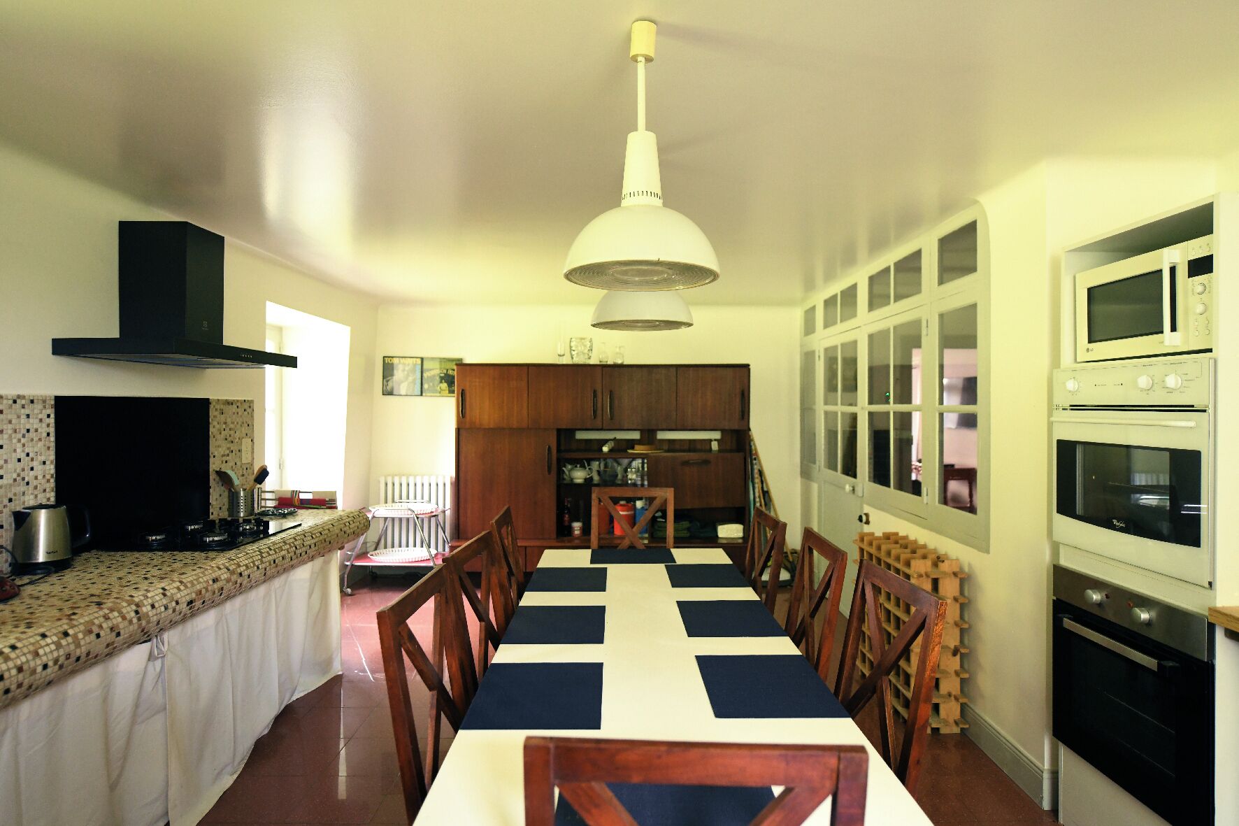A kitchen with a dining table, chairs, and a hanging light fixture.