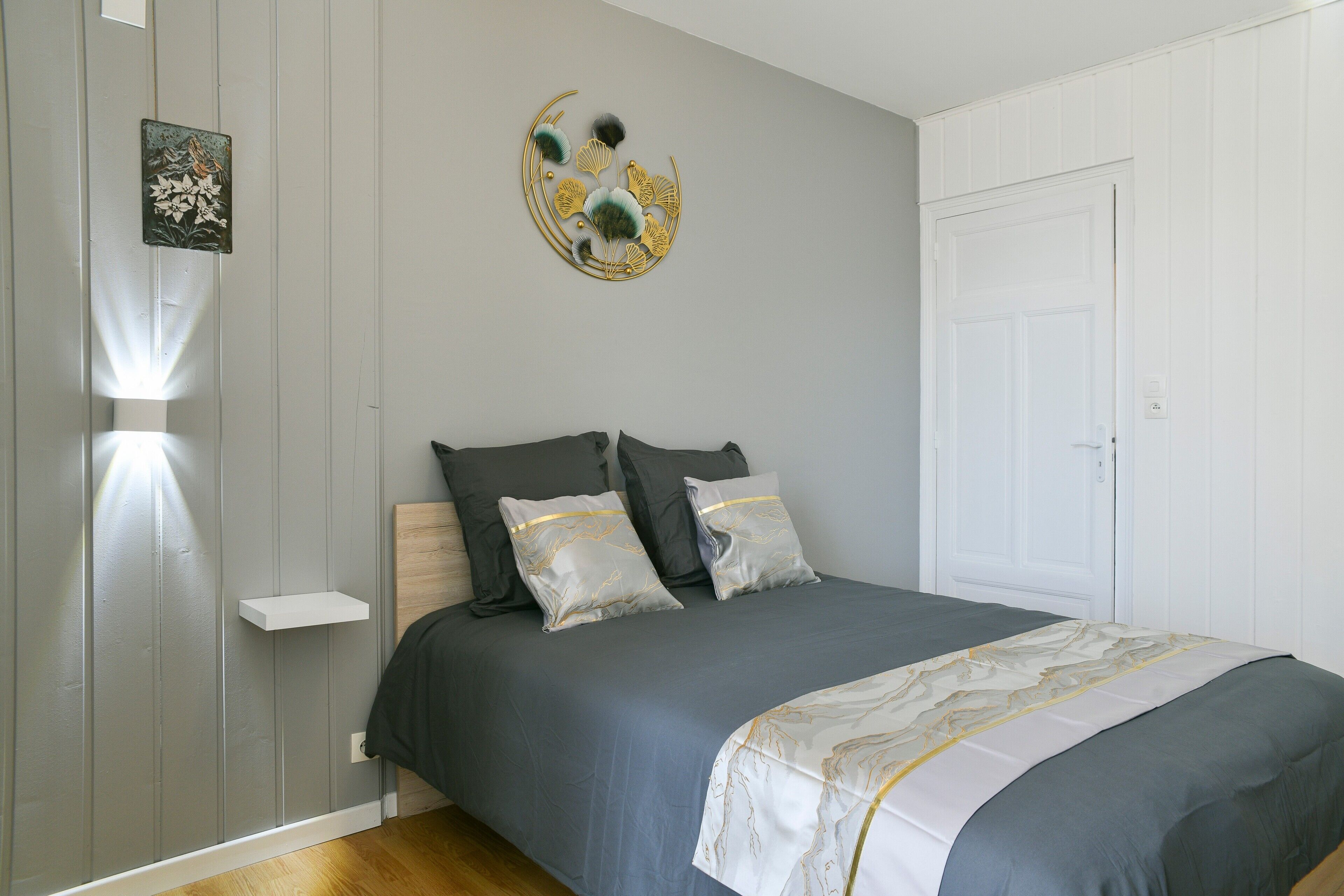 A bedroom with a bed, two pillows, a wall-mounted artwork, and a door.