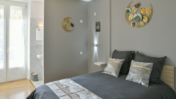 A bedroom with a bed, pillows, a wall-mounted artwork, a bedside table, and a door leading to a bathroom. - Guest Room 5 with Shared Pool, Garden, and Wi-Fi (Betton-Bettonet)