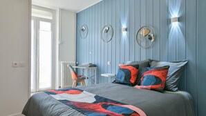 Une chambre à coucher comprenant un lit, une chaise, une petite table et des lampes fixées au mur.