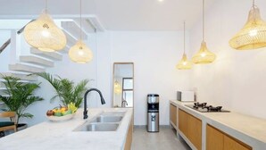 Una cocina moderna con una isla central, electrodomésticos de acero inoxidable y lámparas colgantes de mimbre.