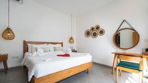 Un dormitorio con una cama de madera, un escritorio y una silla. Hay decoraciones en la pared y una lámpara colgante.
