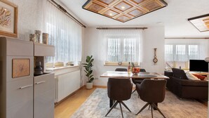 A modern kitchen with a dining area, a sofa, and a TV. - Alpine View Apartment with Mountain Views, Balcony & Wi-Fi (Schopfheim)