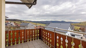 A balcony with a view of a rural landscape, a wooden fence with decorative elements, and a metal railing. - Alpine View Apartment with Mountain Views, Balcony & Wi-Fi (Schopfheim)