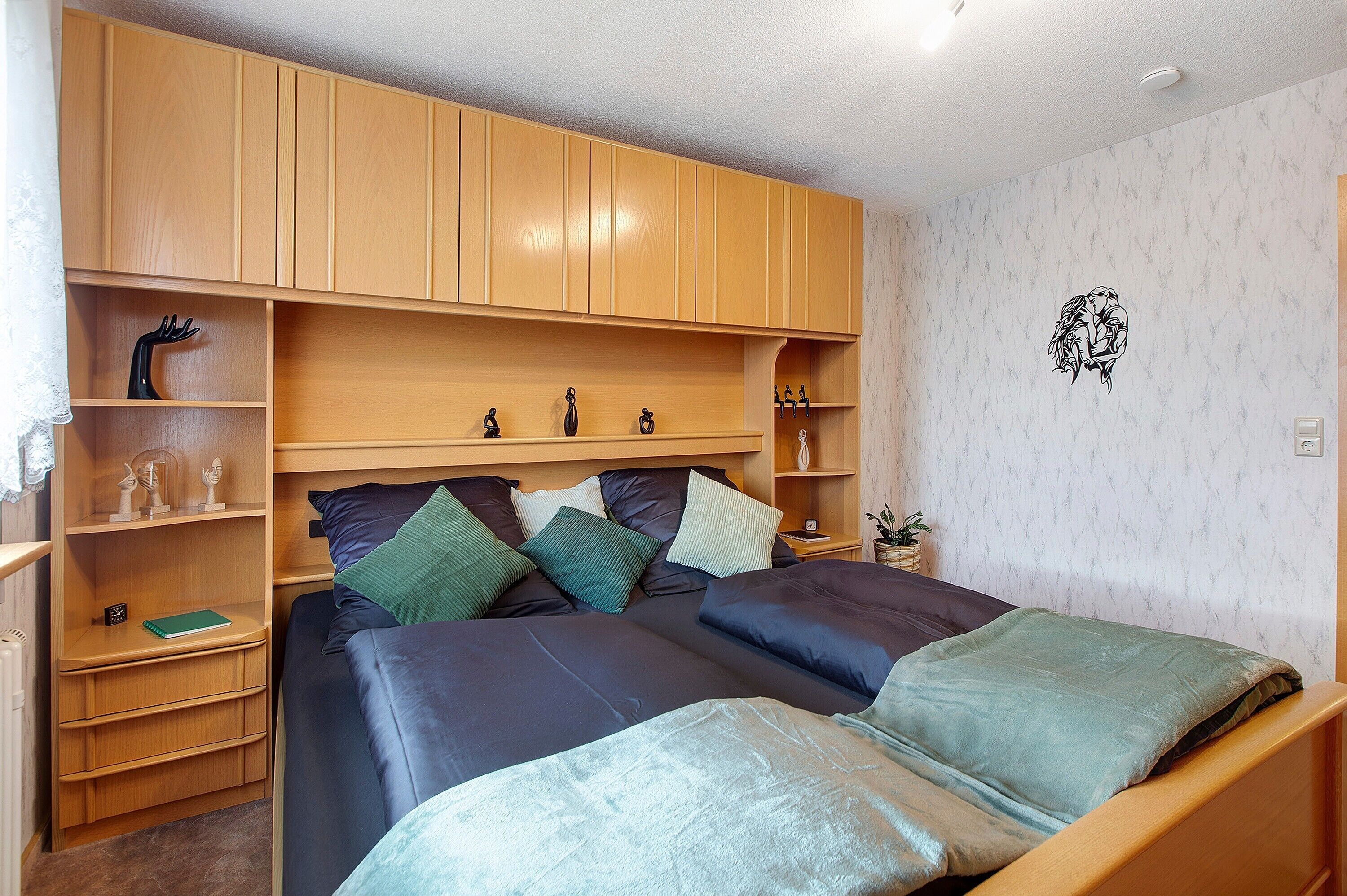A bedroom with a bed, wooden cabinets, and a wall decoration.