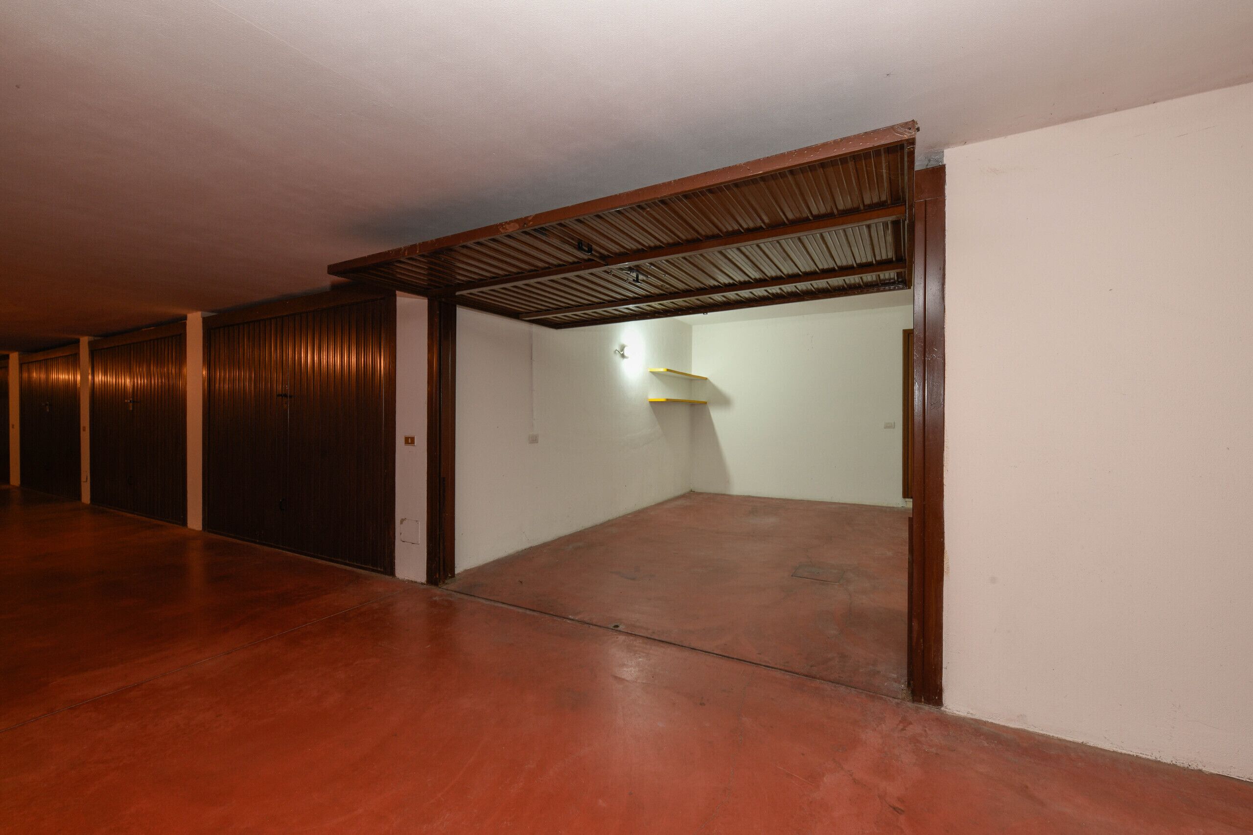 Un pasillo con puertas de madera y suelo de hormigón.