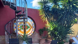 Ein Patio mit einer Wendeltreppe, einem runden Tisch mit Stühlen und Topfpflanzen.
