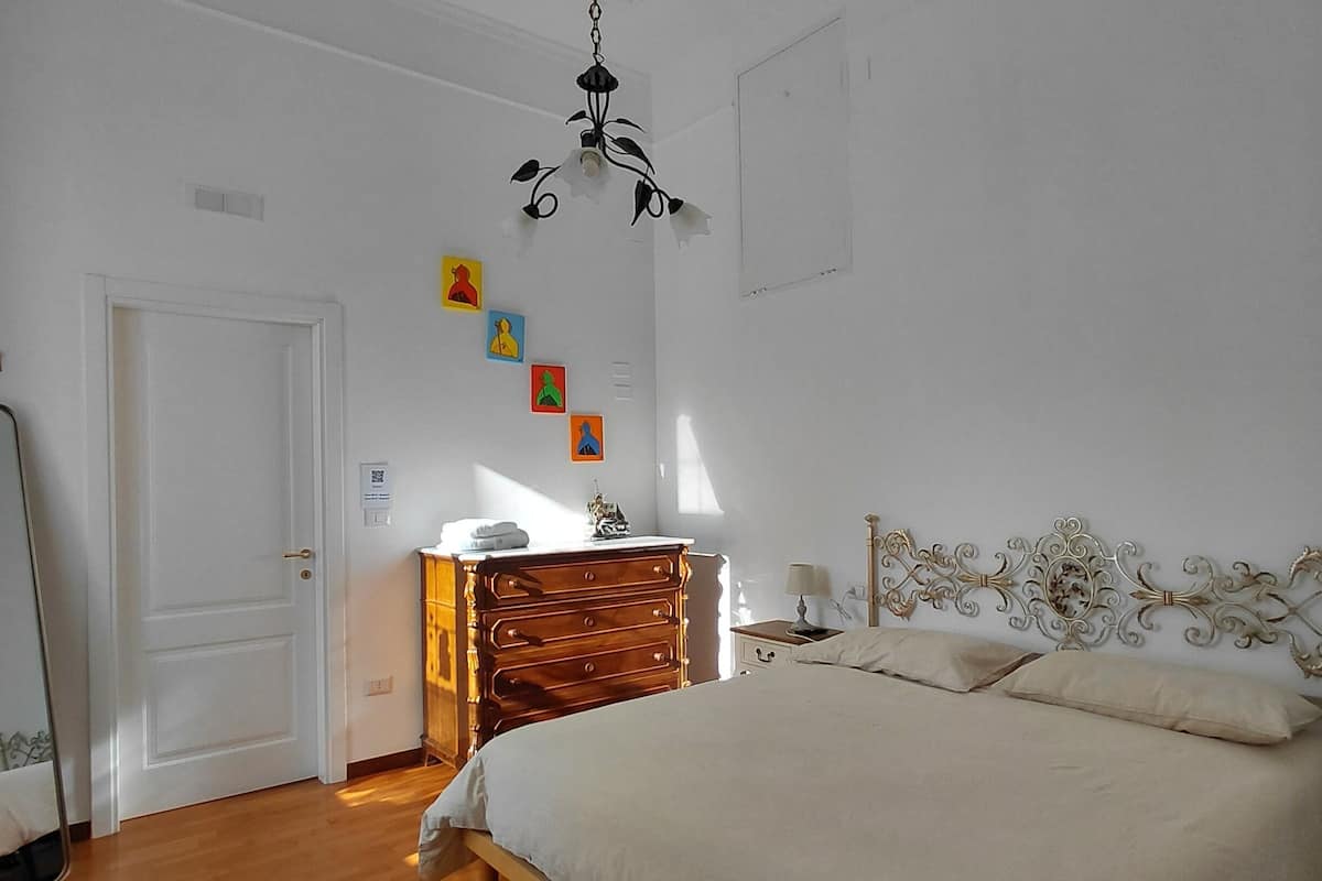 Una camera da letto con un letto di legno, una cassettiera, uno specchio e un lampadario.
