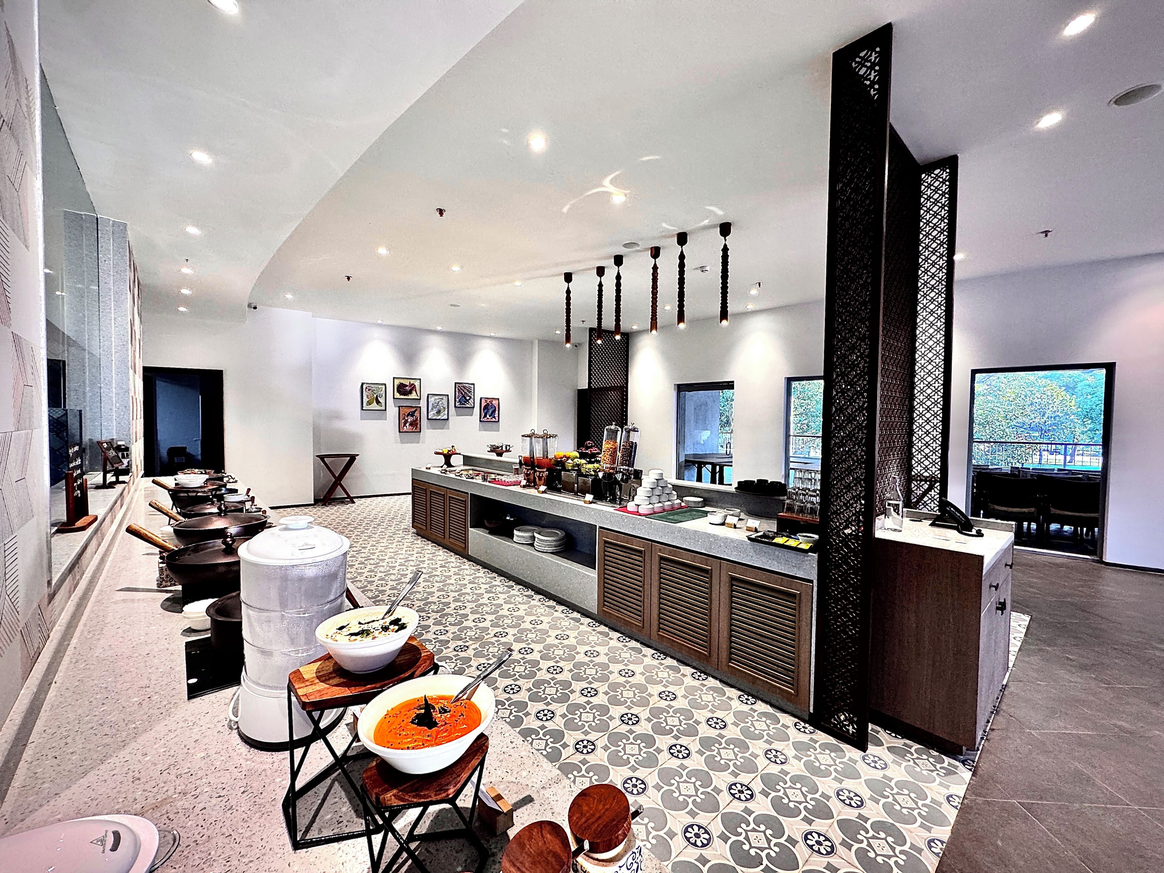 A modern kitchen with a central island, a dining area with a patterned floor, and a large window offering a view.