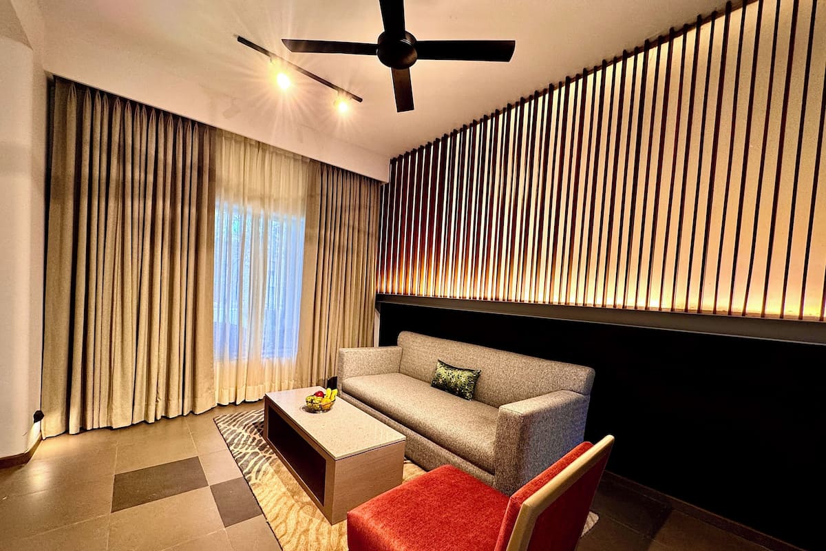Ein modernes Wohnzimmer mit einer Couch, einem roten Sessel, einem Couchtisch und einem Deckenventilator.