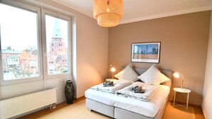 Een slaapkamer met een bed, twee nachtkastjes, een radiator, een raam en een hanglamp.