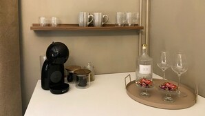Un comptoir de cuisine avec une machine à café, des bocaux, une bouteille d’eau et des verres à vin.
