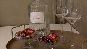 Un plateau avec une bouteille d’eau, deux verres et deux petits bols de biscuits.