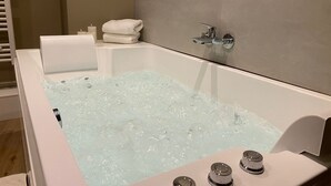 Une salle de bain moderne avec une baignoire remplie d’eau, un porte-serviettes et un support à papier toilette.