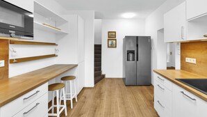 A modern kitchen with white cabinets, wooden countertops, a stainless steel refrigerator, and a built-in oven. - Spacious Renovated House in Wolfsthal, Austria - Perfect for Families and Groups (Wolfsthal)