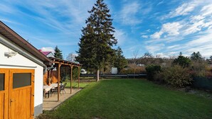 A backyard with a wooden pergola, a lawn, and a tall evergreen tree. - Spacious Renovated House in Wolfsthal, Austria - Perfect for Families and Groups (Wolfsthal)