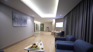 A modern hotel lobby with a reception desk, seating area, and a large abstract painting on the wall.