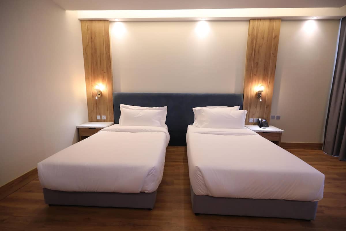 A double room with two beds, wooden headboard, bedside lamps, and a wooden floor.