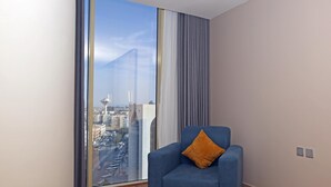 A modern room with a large window, a blue armchair with a cushion, and a view of a cityscape.