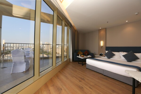 A modern hotel room with a large balcony, a bed, a small table, and a sofa.