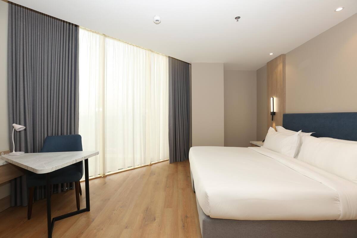 A hotel room with a bed, a desk, and a chair.