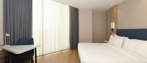 A hotel room with a bed, a desk, and a chair.
